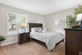 Greensboro apartment for rent - A bedroom with a bed, nightstand, and a plant.