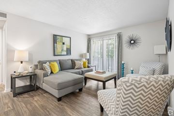 Winston-Salem apartment for rent - A living room with a grey couch, a grey armchair, and a small table with a lamp on it.