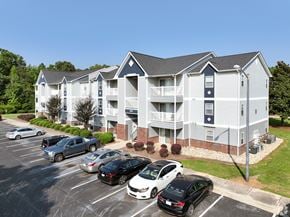 Monroe apartment for rent - A parking lot with cars and a building in the background.