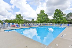 Monroe apartment for rent - A large outdoor swimming pool surrounded by trees and a fence.