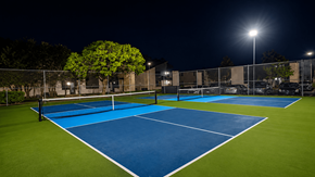 Lawton apartment for rent - A tennis court at night with lights on.