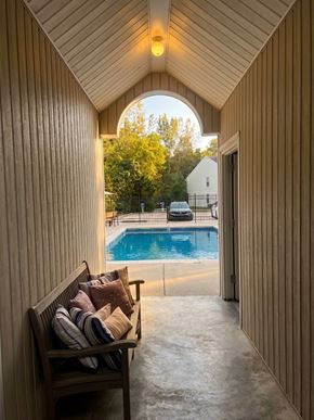 Blue Springs townhouse for rent - A wooden bench with cushions is placed in a hallway with a pool visible through an archway.