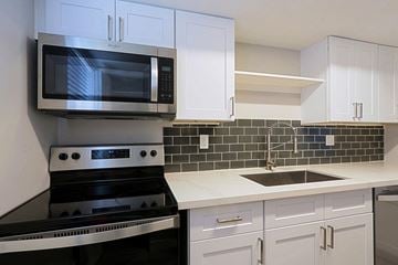 Phoenix apartment for rent - A modern kitchen with white cabinets and a black stove top oven.