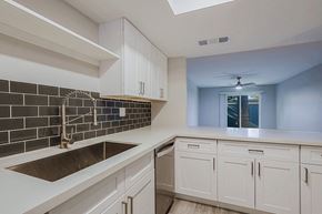 Phoenix apartment for rent - A kitchen with white cabinets and a black tile backsplash.