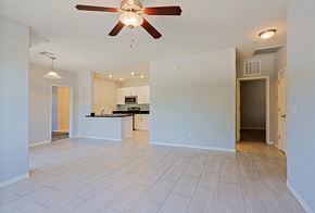 Chandler apartment for rent - an empty living room with a ceiling fan and a kitchen