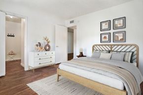 Phoenix apartment for rent - A bedroom with a large bed and a dresser with a mirror at Foothills Court Apartments, Phoenix, AZ 85029