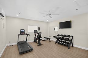 Yuma apartment for rent - A spacious home gym with a treadmill, exercise bike, bench, and dumbbells.
