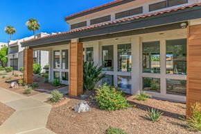 Mesa apartment for rent - the front of a building with plants and rocks in front of it at Saltéra Apartments, Arizona