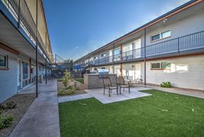 Tempe apartment for rent - a patio with a grill and chairs in front of a building