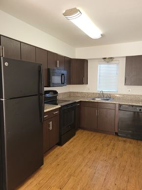 Tempe apartment for rent - an empty kitchen with wooden floors and black appliances