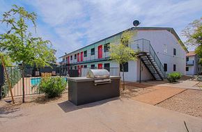 Phoenix apartment for rent - a backyard with a grill and a pool in front of a white building with red and green
