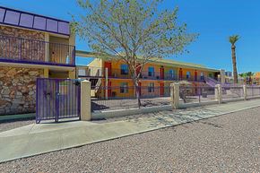 Phoenix apartment for rent - A building with a purple fence and a tree in front.