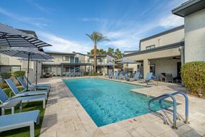 Phoenix apartment for rent - A swimming pool surrounded by lounge chairs and umbrellas.