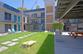 Mesa apartment for rent - A patio with a table and chairs is surrounded by a grassy area and a building.