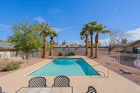 Phoenix apartment for rent - A pool surrounded by palm trees and chairs.