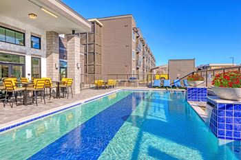 A swimming pool with tables and chairs next to a building