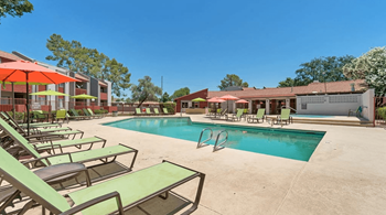 Angular shaped pool with green chaise lounge chairs facing the resident clubhouse