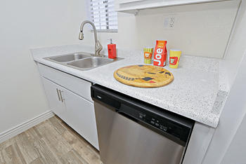 Kitchen countertop area with double sided sink, white cabinetry, and a stainless steel dishwasher