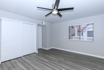 Large bedroom with plank flooring, oversized window, and ceiling fan 
