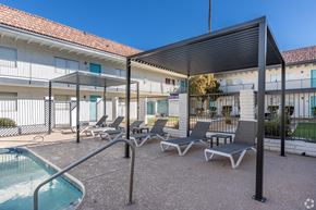 Mesa apartment for rent - a patio with lounge chairs and a pool and a building