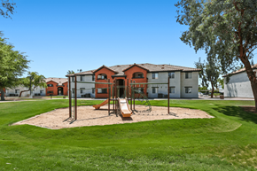 Yuma apartment for rent - A playground with a swing set and sandbox in front of a building.
