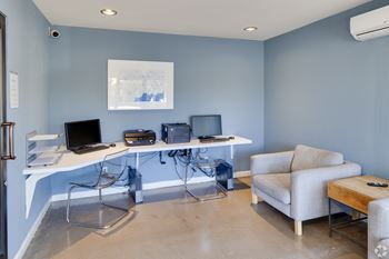A room with a desk, chairs, and a couch.