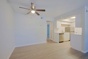 Phoenix triplex for rent - an empty living room with a ceiling fan and a kitchen