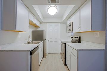 Phoenix triplex for rent - a kitchen with white cabinets and stainless steel appliances and white counter tops