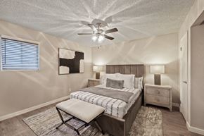 Phoenix apartment for rent - A bedroom with a bed, chair, and ceiling fan.