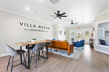 Yuma apartment for rent - A living room with a dining table and chairs in front of a wall that says "VILLA NUEVA APARTMENTS".