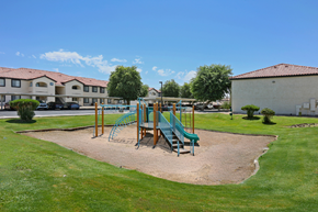 Yuma apartment for rent - A playground with a green slide and a blue slide in the middle of a sand pit.