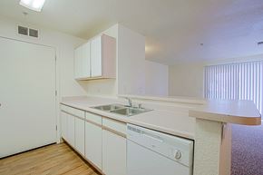 Yuma apartment for rent - A white kitchen with wooden floors and a dishwasher.