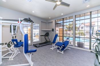 Fitness center with various machines and weights with view of soothing swimming pool