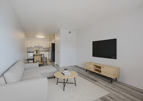 Phoenix apartment for rent - A living room with a white couch, a coffee table, and a TV mounted on the wall.