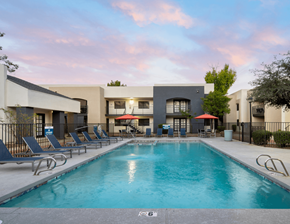 Phoenix apartment for rent - A swimming pool surrounded by lounge chairs and a building in the background.