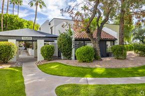 Scottsdale apartment for rent - A building with a black awning and a sign that says "BARBERSHOP" is surrounded by greenery.