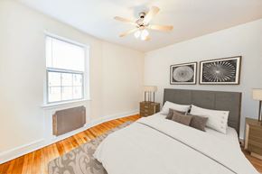 Washington apartment for rent - bedroom with bed, nightstand, ceiling fan and  large window at 2800 ontario road apartments in washington dc