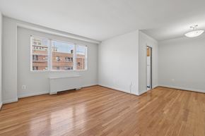 Bethesda apartment for rent - Empty room with wooden floors and a window showing an apartment building outside.