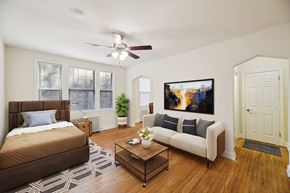 Washington apartment for rent - A bedroom with a brown bed and a white couch with a painting on the wall.