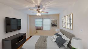 Washington apartment for rent - bedroom with bed, nightstands, dresser, tv, ceiling fans and large windows at alpha house apartments in washington dc