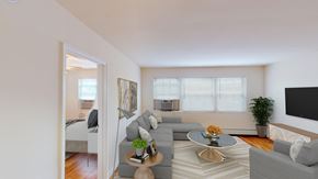 Washington apartment for rent - living area with sofa, coffee table, credenza, tv, large windows, view of bedroom hardwood floors at alpha house apartments in washington dc