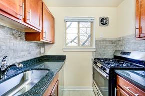 Bethesda apartment for rent - kitchen with wood cabinetry, gas range, tile backsplash, and window at cambridge square apartments in bethesda md