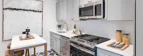 Washington apartment for rent - kitchen with white cabinetry, stainless steel appliances, microwave and kitchen island at the dahlia apartments in washington dc