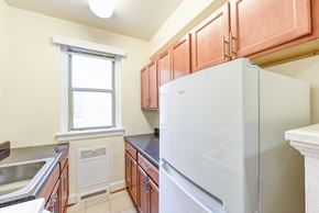 Washington apartment for rent - kitchen with wood cabinetry, electric range, refrigerator, and window at eddystone apartments in washington dc