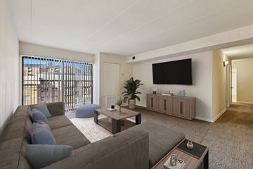 Washington apartment for rent - A living room with a grey couch and a flat screen TV mounted on the wall.