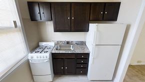 Washington apartment for rent - A kitchen with a white stove and refrigerator, and dark brown cabinets.