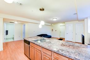 Washington apartment for rent - open kitchen with large kitchen island, hardwood floors, and view of living area at park vista apartments in washington dc