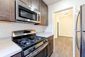 Washington apartment for rent - kitchen with espresso cabinetry, view of dining area and stainless steel appliances at petworth station apartments in washington dc