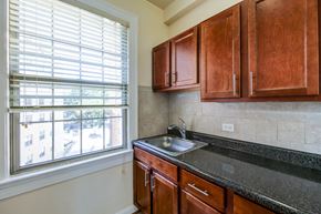 Washington apartment for rent - kitchen with large window, oak cabinetry and tile backsplash at the frontenac apartments in van ness washington dc