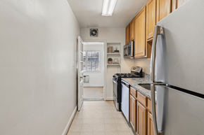 Chevy Chase apartment for rent - A kitchen with a white refrigerator, black dishwasher, and wooden cabinets.